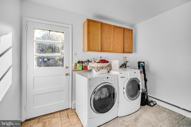 clothes washing area featuring baseboard heating, washing machine and dryer, light parquet floors, and cabinets