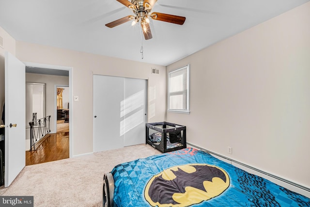 carpeted bedroom featuring ceiling fan, baseboard heating, and a closet