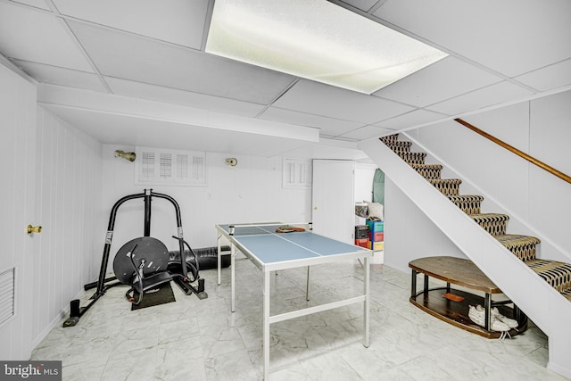 playroom featuring a drop ceiling and wood walls