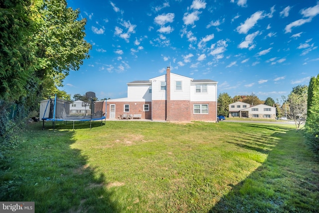 rear view of house featuring a yard, a trampoline, and a patio