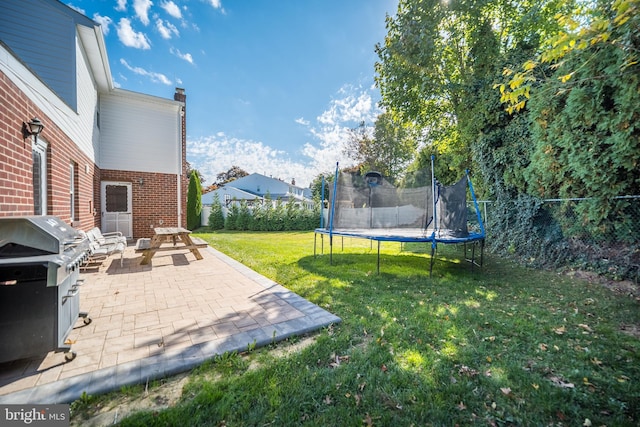 view of yard with a trampoline and a patio