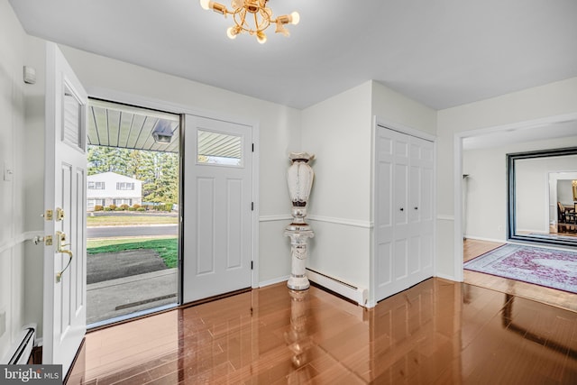 entrance foyer with hardwood / wood-style floors, an inviting chandelier, and baseboard heating