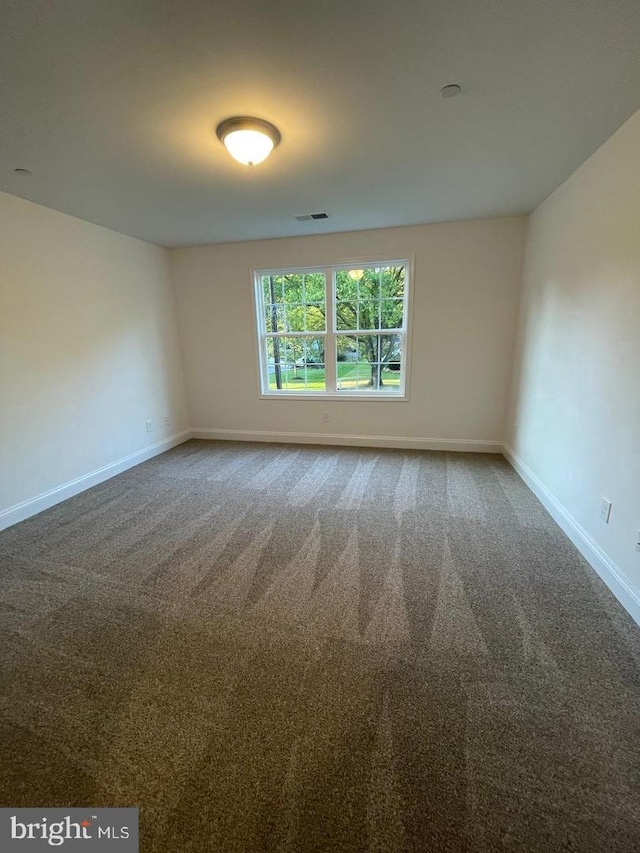 carpeted empty room featuring visible vents and baseboards