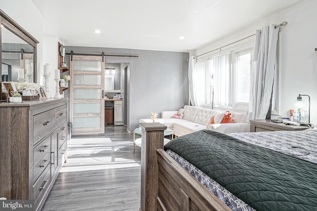 bedroom featuring a barn door and dark wood-type flooring