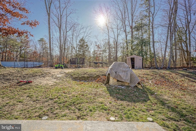 view of yard with a pool, a trampoline, and a shed