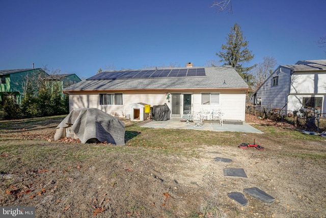 rear view of house featuring solar panels, a yard, and a patio area