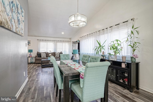 dining space featuring dark hardwood / wood-style flooring, lofted ceiling, and a chandelier