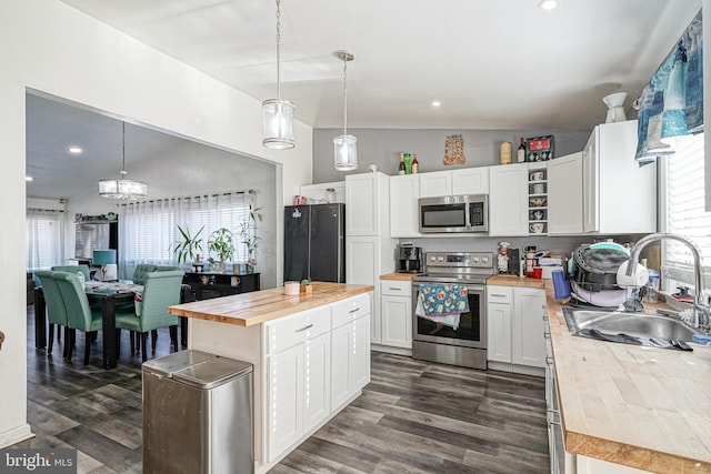 kitchen featuring sink, butcher block countertops, pendant lighting, white cabinets, and appliances with stainless steel finishes