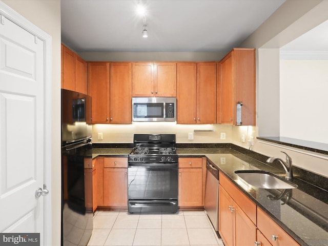 kitchen with sink, dark stone countertops, light tile patterned floors, black appliances, and crown molding