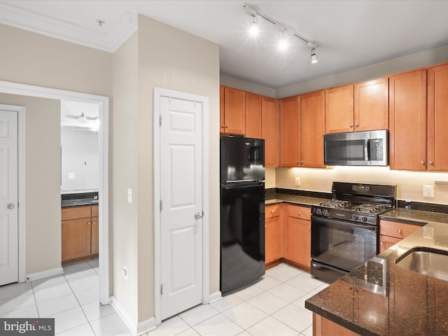 kitchen with sink, light tile patterned floors, crown molding, black appliances, and dark stone counters