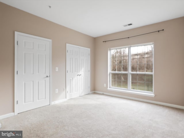 unfurnished bedroom featuring light carpet and a closet