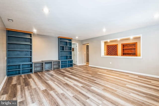 unfurnished living room featuring light wood-type flooring and built in features