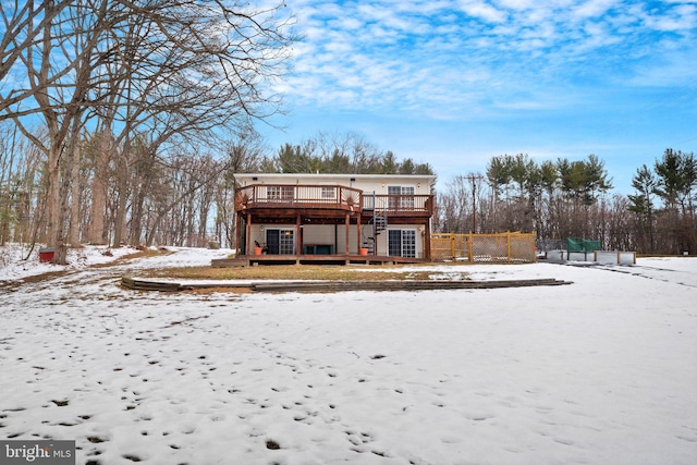 snow covered rear of property with a deck