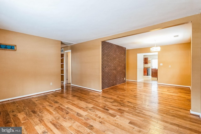 empty room with brick wall and light hardwood / wood-style flooring