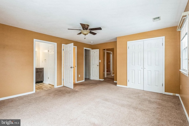 unfurnished bedroom with ceiling fan, light colored carpet, and ensuite bath