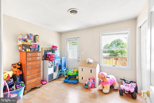 playroom with a textured ceiling and light wood-type flooring