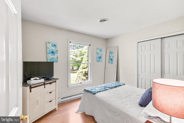 bedroom with a baseboard radiator, light hardwood / wood-style floors, and a closet