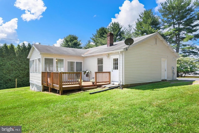 rear view of house with a deck, a yard, and a sunroom