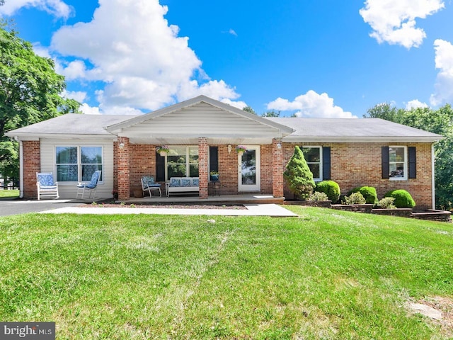 ranch-style home featuring covered porch and a front lawn