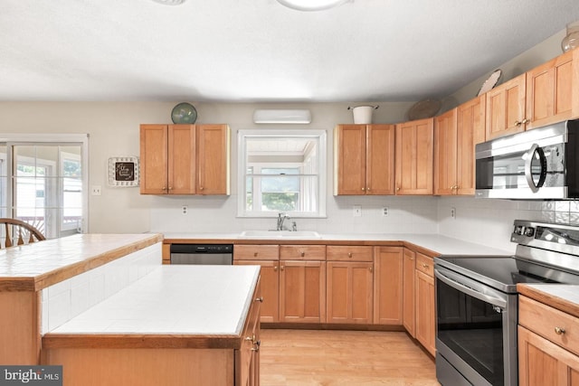 kitchen featuring sink, a center island, tile countertops, and appliances with stainless steel finishes