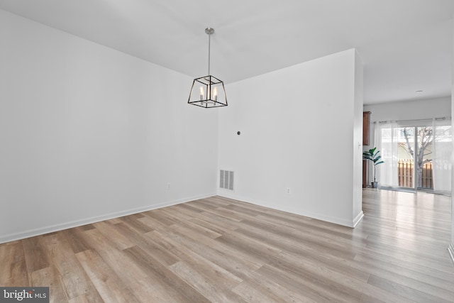 unfurnished dining area with light hardwood / wood-style floors and an inviting chandelier