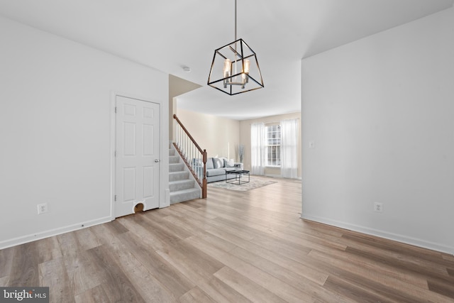 unfurnished living room featuring light wood-type flooring and an inviting chandelier