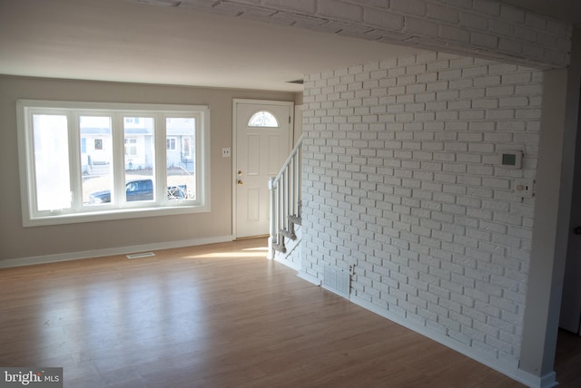 entryway with plenty of natural light, light hardwood / wood-style floors, and brick wall