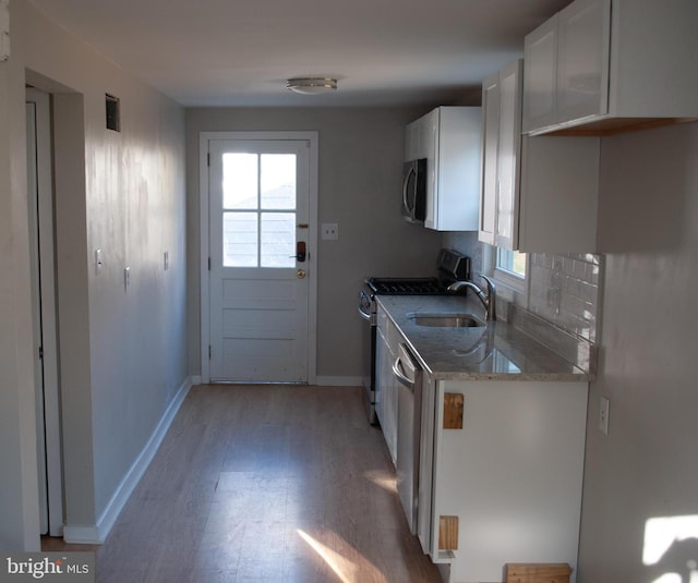 kitchen featuring white cabinetry, sink, tasteful backsplash, light hardwood / wood-style flooring, and appliances with stainless steel finishes