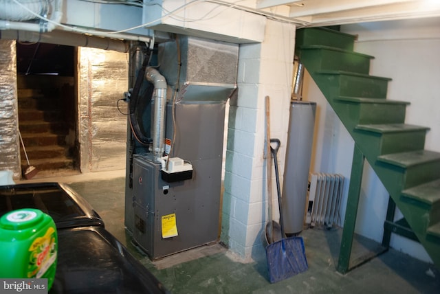 utility room featuring heating unit, gas water heater, and radiator