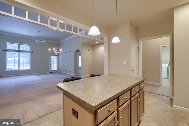 kitchen with washer / clothes dryer, a center island, light carpet, and decorative light fixtures