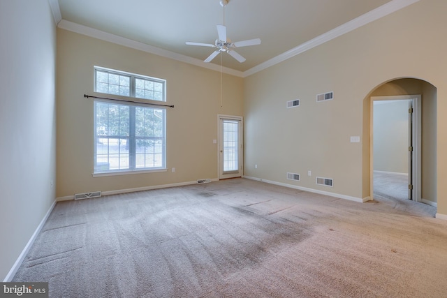 unfurnished room featuring light carpet, crown molding, ceiling fan, and a high ceiling