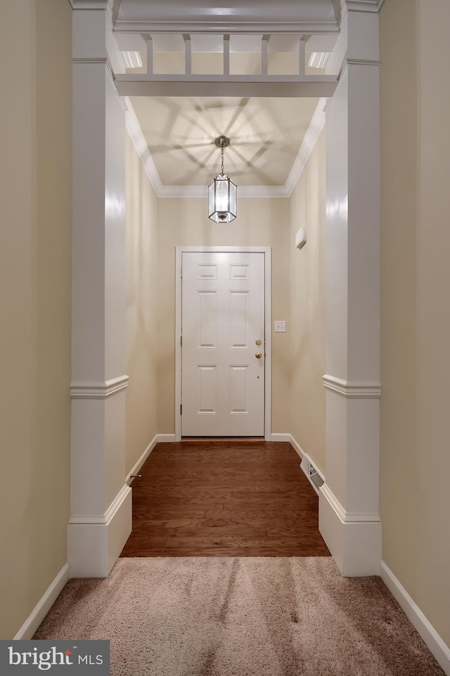 doorway with crown molding, a chandelier, and carpet flooring