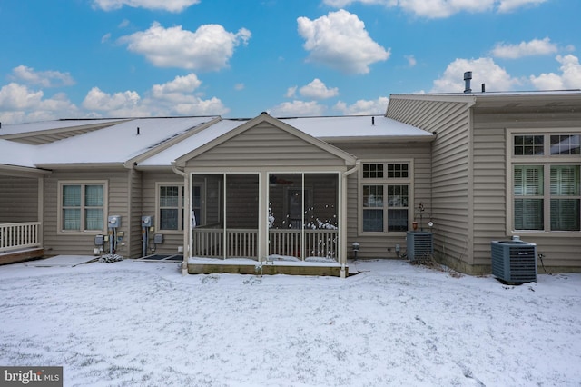 snow covered house featuring a sunroom and central air condition unit