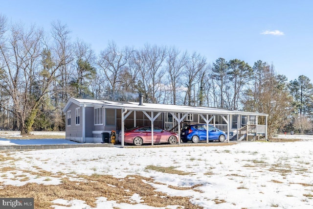 snow covered parking with a carport