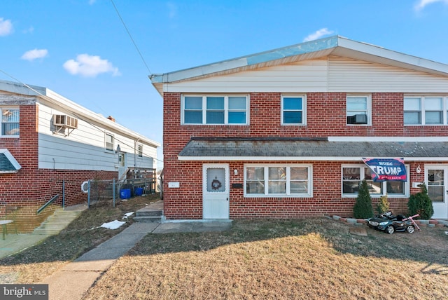 townhome / multi-family property with a front yard and a wall mounted AC