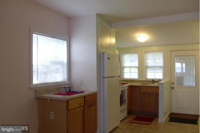 kitchen featuring light tile patterned flooring, stove, white refrigerator, and sink