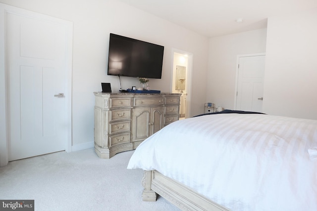 bedroom featuring light carpet and connected bathroom