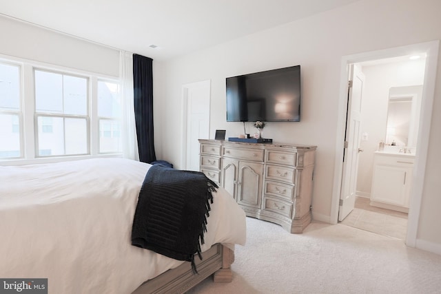 bedroom featuring light carpet and ensuite bath