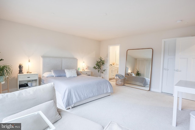 bedroom featuring ensuite bath and light carpet