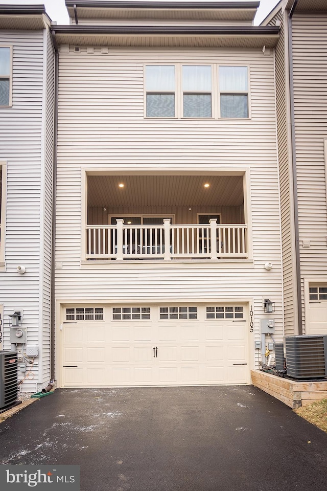 view of front of property with a balcony, a garage, and central AC unit