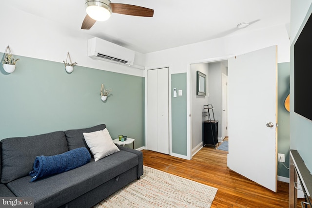 living room featuring ceiling fan, a wall mounted AC, and wood-type flooring