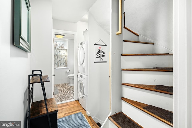 stairs with stacked washer / dryer and hardwood / wood-style floors