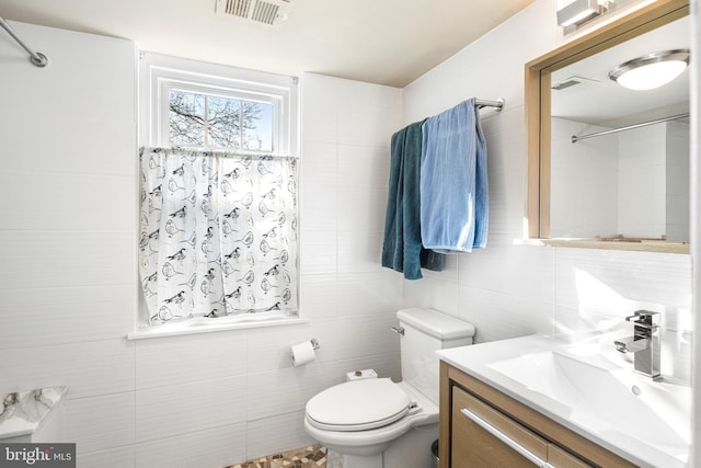 bathroom featuring tile walls, toilet, and vanity