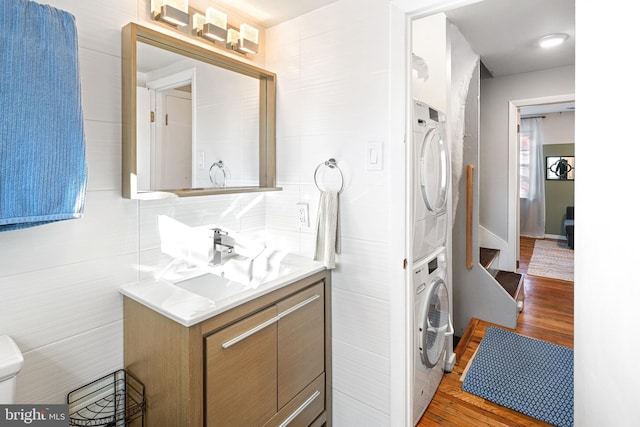 bathroom featuring hardwood / wood-style floors, vanity, and stacked washing maching and dryer