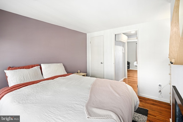 bedroom featuring dark wood-type flooring and a wall mounted air conditioner