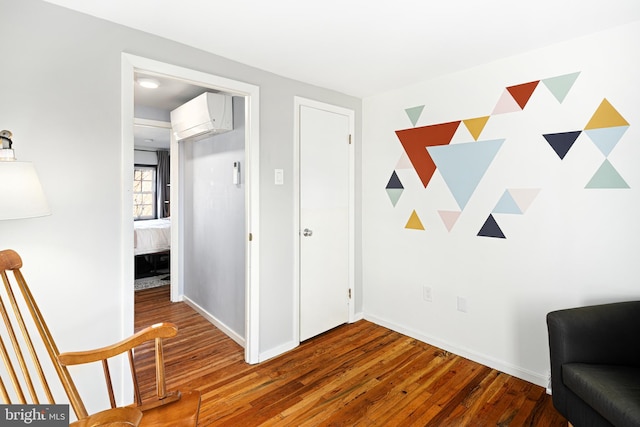 sitting room with hardwood / wood-style flooring and a wall unit AC