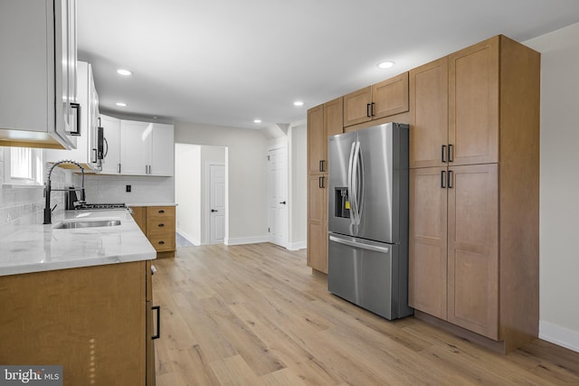 kitchen featuring light stone countertops, light hardwood / wood-style flooring, stainless steel appliances, white cabinets, and sink