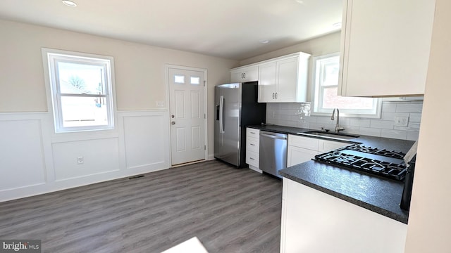 kitchen with sink, dark wood-type flooring, decorative backsplash, white cabinets, and appliances with stainless steel finishes