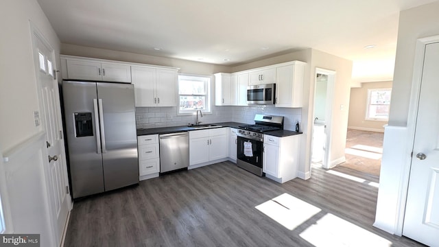 kitchen featuring decorative backsplash, dark hardwood / wood-style flooring, stainless steel appliances, sink, and white cabinetry