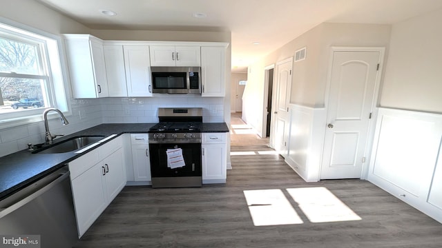 kitchen with white cabinets, backsplash, sink, and appliances with stainless steel finishes